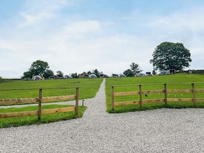 A gravel path leading to a grassy field with wooden fences and transparent structures. - Weets Hill Dome - UKC9598 (Earby)