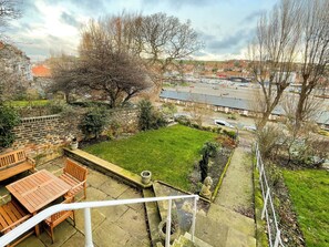 A residential area with a grassy backyard, a stone wall, and a view of a parking lot and buildings in the distance. - 4 bedroom accommodation in Whitby (Whitby)
