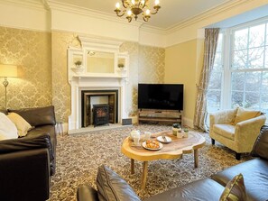 A living room with a fireplace, television, and seating area. - 4 bedroom accommodation in Whitby (Whitby)