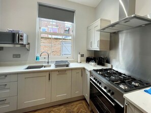 A modern kitchen with a gas stove, a microwave, and a sink. - 4 bedroom accommodation in Whitby (Whitby)