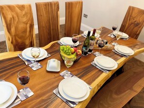 A wooden dining table set for six with plates, glasses, cutlery, and a fruit basket. - 4 bedroom accommodation in Whitby (Whitby)