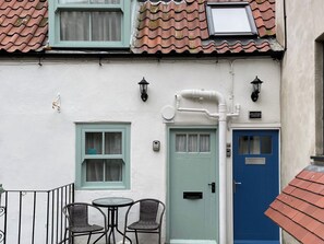 A white building with a blue door and a small balcony with two wicker chairs. - 2 bedroom accommodation in Whitby (Whitby)
