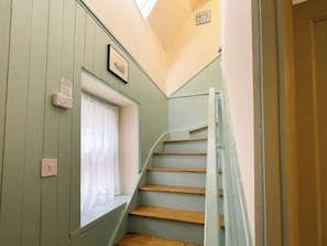 A staircase with wooden steps and a white handrail, leading to a landing with a window and a picture frame. - 2 bedroom accommodation in Whitby (Whitby)