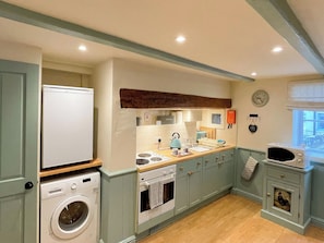 A compact kitchen with a washing machine, oven, microwave, and a sink. - 2 bedroom accommodation in Whitby (Whitby)