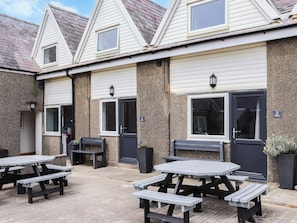 A building with a covered patio area featuring picnic tables and benches. - 2 bedroom accommodation in Llanengan (Llanengan)
