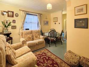 A living room with a sofa, chairs, a dining table with chairs, a patterned rug, and framed pictures on the walls. - 2 bedroom accommodation in Whitby (Whitby)