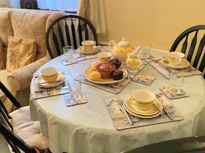A dining table set with yellow and white tea sets, plates, and a teapot. - 2 bedroom accommodation in Whitby (Whitby)