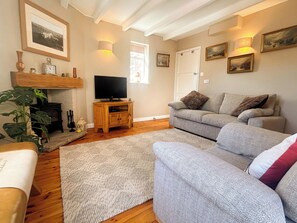 A living room with a sofa, a television, a fireplace, and a plant. - 1 bedroom accommodation in Whitby (Whitby)
