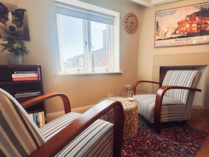 A cozy living room with striped armchairs, a bookshelf, a clock, and a fireplace. - 1 bedroom accommodation in Whitby (Whitby)
