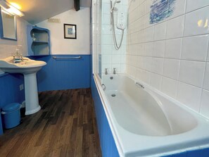 Une salle de bain avec une baignoire blanche, un lavabo et un miroir.