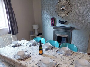 A dining room with a table set for four, a fireplace, and a patterned wall. - 4 bedroom accommodation in Whitby (Whitby)