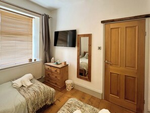 A bedroom with a bed, dresser, mirror, television, and a wooden door. - 3 bedroom accommodation in Whitby (Whitby)