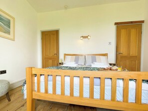 Un dormitori amb un llit de fusta, dues portes, una taula de nit i un llum penjada a la paret.