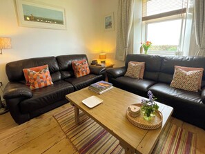 A living room with two black leather sofas, a wooden coffee table, and a striped rug. - 3 bedroom accommodation in Whitby (Whitby)