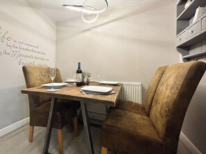 Ein Essbereich mit einem Tisch für zwei Personen, einer Weinflasche und einer Ananas auf dem Tisch.