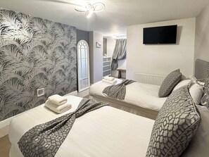 Une chambre d’hôtel avec deux lits, une télévision, un miroir et un mur décoré d’un motif.