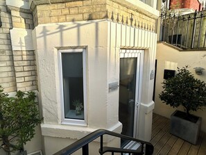 A corner of a building with a window and a door, a potted plant, and a metal railing. - 2 bedroom accommodation in Whitby (Whitby)