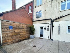 A residential building with a brick facade, a wooden fence, and a tiled patio area. - 2 bedroom accommodation in Whitby (Whitby)