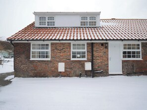 A two-story brick building with a tiled roof, a white door, and two windows on the ground floor. - 2 bedroom accommodation in Whitby (Whitby)