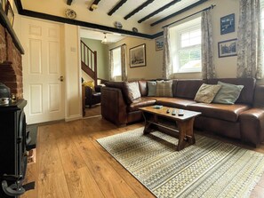 A cozy living room with a brown leather sofa, a wooden coffee table, and a patterned rug. - 2 bedroom accommodation in Whitby (Whitby)