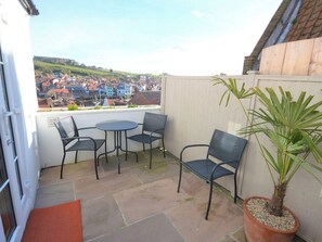 Un patio con tavolo e sedie, una pianta in vaso e vista su una città.