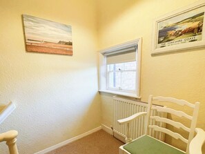 A corner room with a radiator, a window, a chair, and two framed pictures on the wall. - 2 bedroom accommodation in Whitby (Whitby)