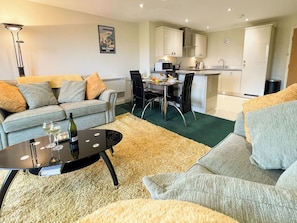 Ein modernes Wohnzimmer mit einer Couch, einem Couchtisch und einem Essbereich mit Stühlen und Tisch.