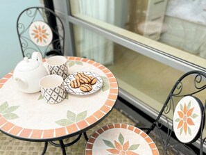 Une table avec une théière, deux tasses décorées et une assiette de biscuits.