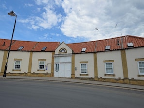 A building with a red-tiled roof, multiple windows, and a central entrance. - 2 bedroom accommodation in Whitby (Whitby)