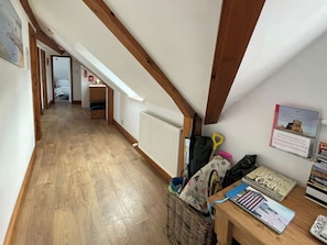 A hallway with wooden flooring, a radiator, and a table with books and a map. - 2 bedroom accommodation in Whitby (Whitby)
