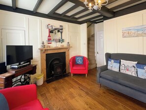 A living room with a fireplace, a television, a red chair, and a grey sofa. - 3 bedroom accommodation in Whitby (Whitby)