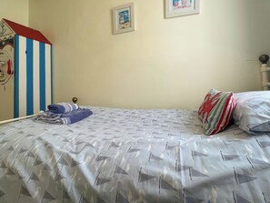 A bed with a geometric patterned bedspread, a striped wall decoration, and two framed pictures on the wall. - 3 bedroom accommodation in Whitby (Whitby)