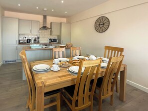 Un comedor con una mesa de madera dispuesta para cuatro personas, rodeada de sillas de madera.