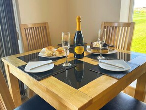 A dining table with a bottle of Prosecco, two plates of food, and two glasses. - 1 bedroom accommodation in Whitby (Whitby)