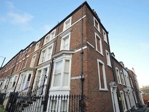 A corner building with a brick facade, white-framed windows, and a black metal fence. - 3 bedroom accommodation in Whitby (Whitby)