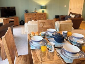 A dining table set with plates, bowls, a teapot, and a glass of orange juice. - 2 bedroom accommodation in Whitby (Whitby)