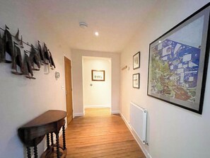 A hallway with wooden flooring, a table, and a large abstract painting on the wall. - 3 bedroom accommodation in Whitby (Whitby)