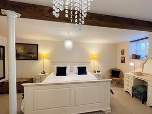A bedroom with a large bed, two bedside lamps, a chandelier, a dresser, a chair, and a window with a view. - 3 bedroom accommodation in Whitby (Whitby)