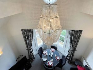 A dining area with a chandelier, table set for four, and black chairs. - 1 bedroom accommodation in Whitby (Whitby)