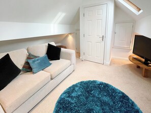 A living room with a sofa, a television, and a door. - 1 bedroom accommodation in Whitby (Whitby)