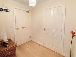 A hallway with two white doors, a wicker basket, and a plant. - 2 bedroom accommodation in Whitby (Whitby)