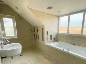 A bathroom with a shower, a sink, a bathtub, and a window with a view of the outdoors. - 3 bedroom accommodation in Whitby (Whitby)