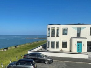 A modern building with a curved facade, a turquoise door, and a view of the sea. - 3 bedroom accommodation in Whitby (Whitby)