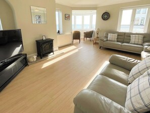 A living room with a television, a sofa, a fireplace, and a view of the outdoors. - 3 bedroom accommodation in Whitby (Whitby)