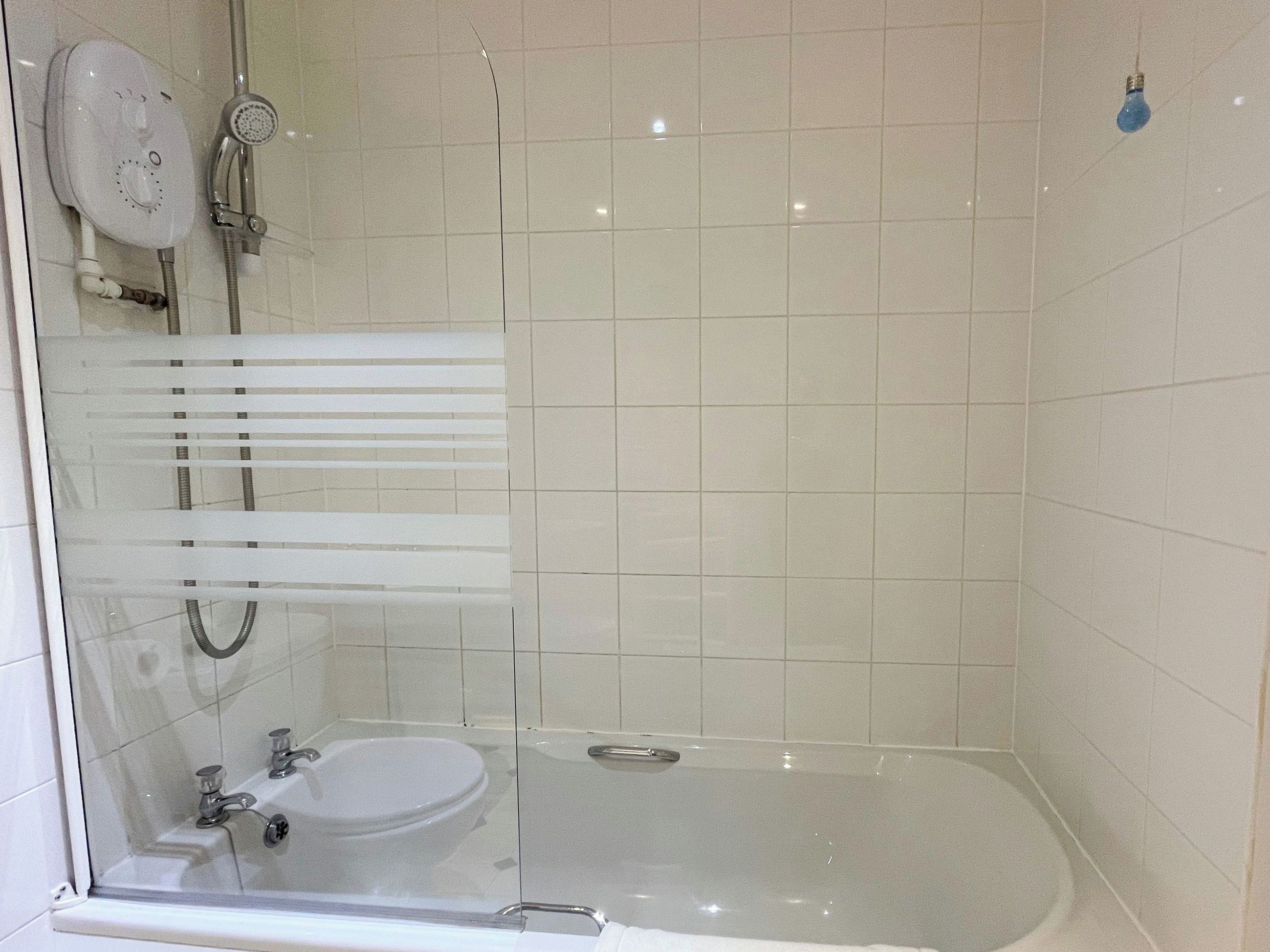 Un bany modern amb dutxa tancada amb vidre, un lavabo blanc i un vàter.