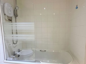 Un baño moderno con ducha de vidrio, lavamanos blanco y un inodoro.