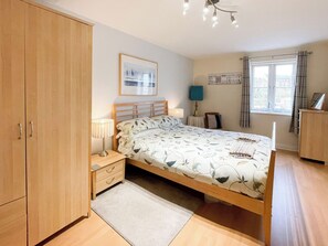 A bedroom with a bed, bedside tables, a wardrobe, a window with curtains, and a wall-mounted picture. - 2 bedroom accommodation in Whitby (Whitby)