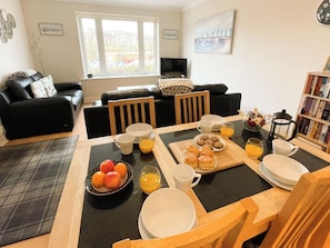 A dining area with a table set for breakfast, including fruits, pastries, and beverages. - 2 bedroom accommodation in Whitby (Whitby)