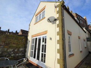 A building with a satellite dish, a large window, and a small outdoor seating area. - 2 bedroom accommodation in Whitby (Whitby)