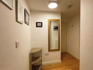 A hallway with a wooden floor, a mirror on the wall, and a door at the end. - 2 bedroom accommodation in Whitby (Whitby)